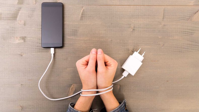手にコードが巻き付いていてスマホに依存している様子を表現